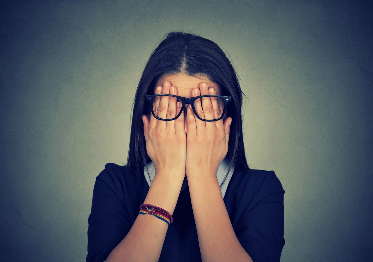 young woman in glasses covering face, eyes